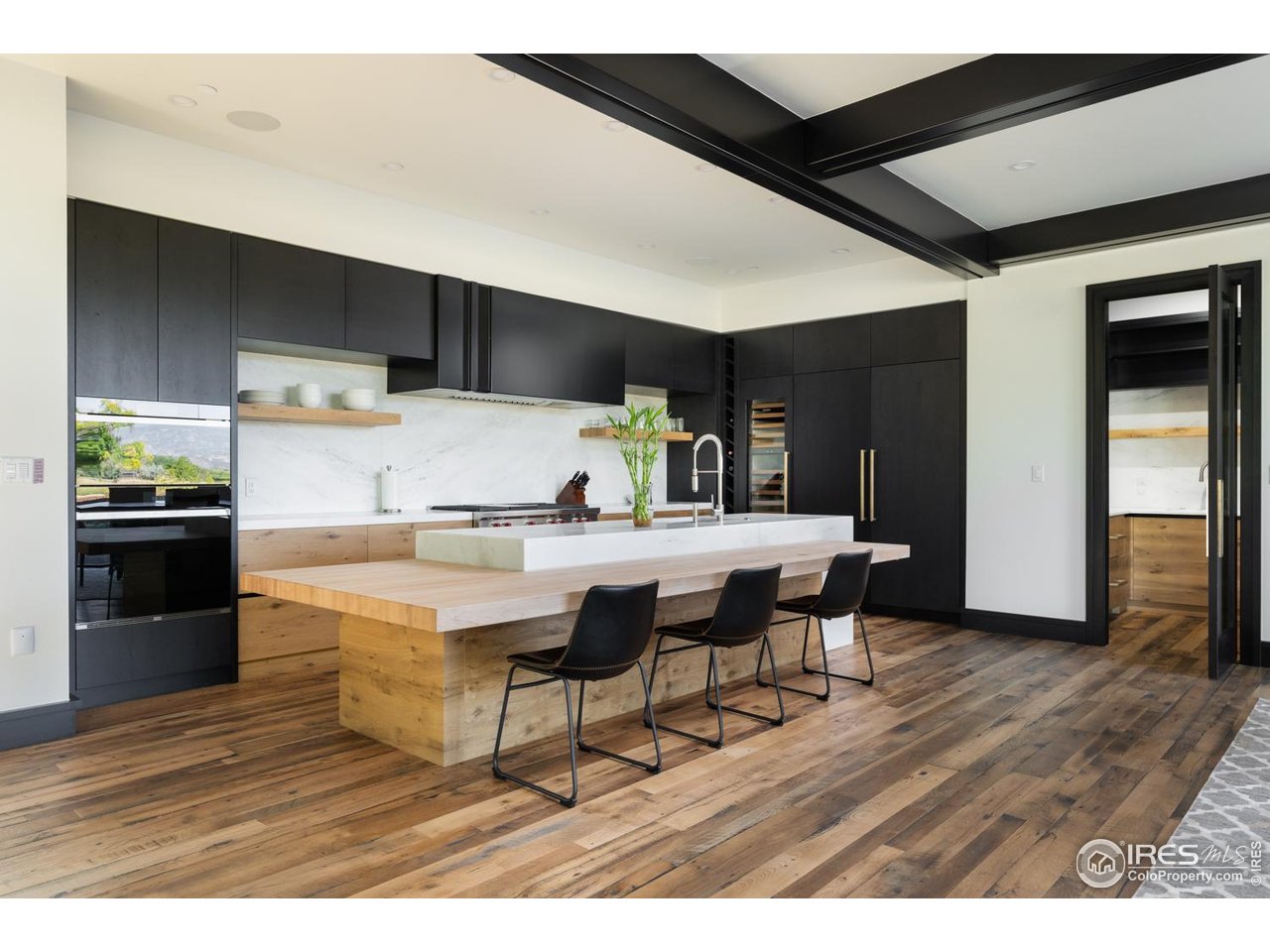 12357 North 75th Street Longmont, CO 80503 - Photo 17 of 49 a kitchen with stainless steel appliances kitchen island granite countertop a table chairs in it and wooden floors