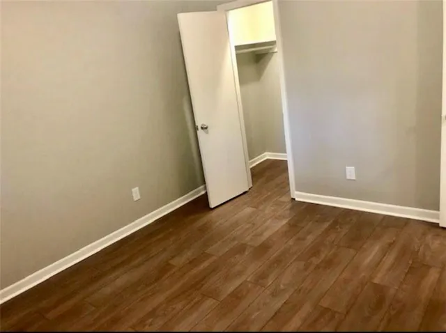 an empty room with wooden floor and mirror
