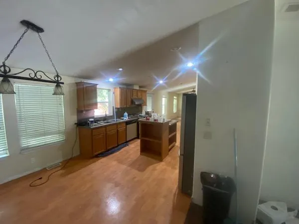a large kitchen with a sink and dishwasher a stove top oven with wooden floor