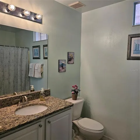 a bathroom with a granite countertop sink mirror vanity and toilet