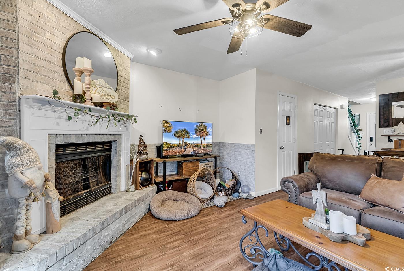 830 44th Avenue North, Unit I5 Myrtle Beach, SC 29577 - Photo 11 of 27 Living area with wood finished floors, a brick fireplace, and a ceiling fan