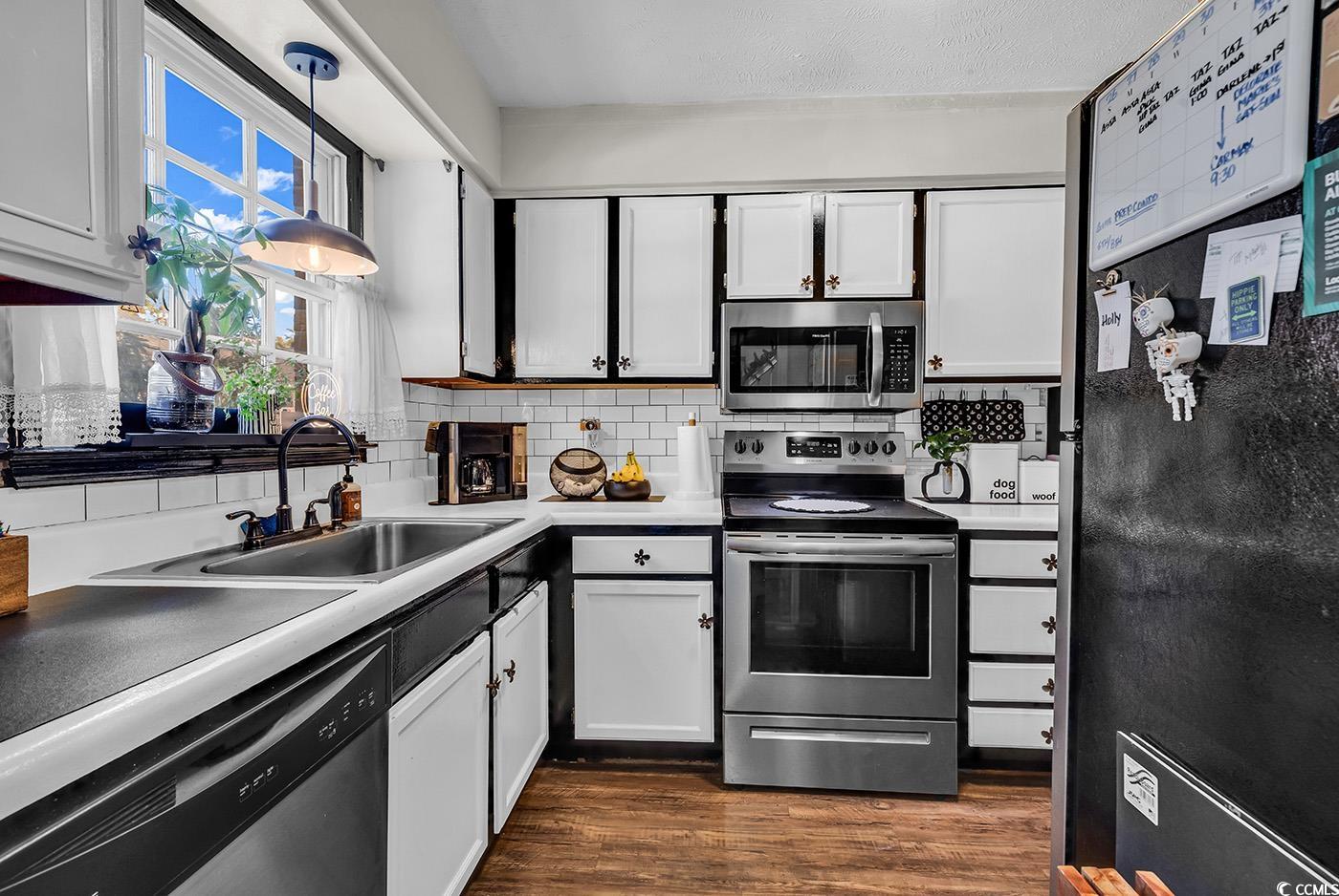 830 44th Avenue North, Unit I5 Myrtle Beach, SC 29577 - Photo 4 of 27 Kitchen with appliances with stainless steel finishes, white cabinetry, backsplash, dark wood finished floors, and light countertops