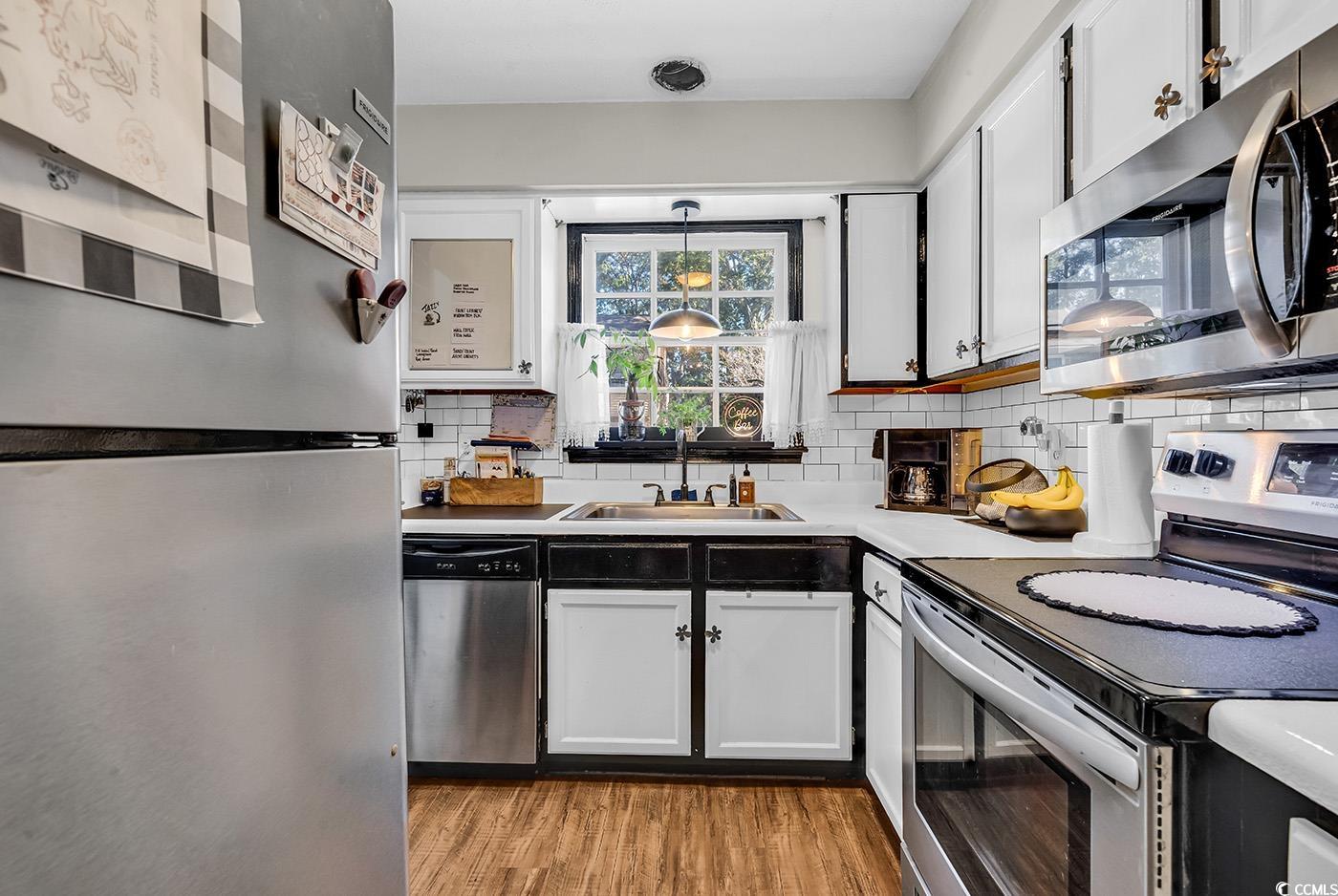 830 44th Avenue North, Unit I5 Myrtle Beach, SC 29577 - Photo 6 of 27 Kitchen featuring stainless steel appliances, pendant lighting, light wood-type flooring, white cabinets, and decorative backsplash