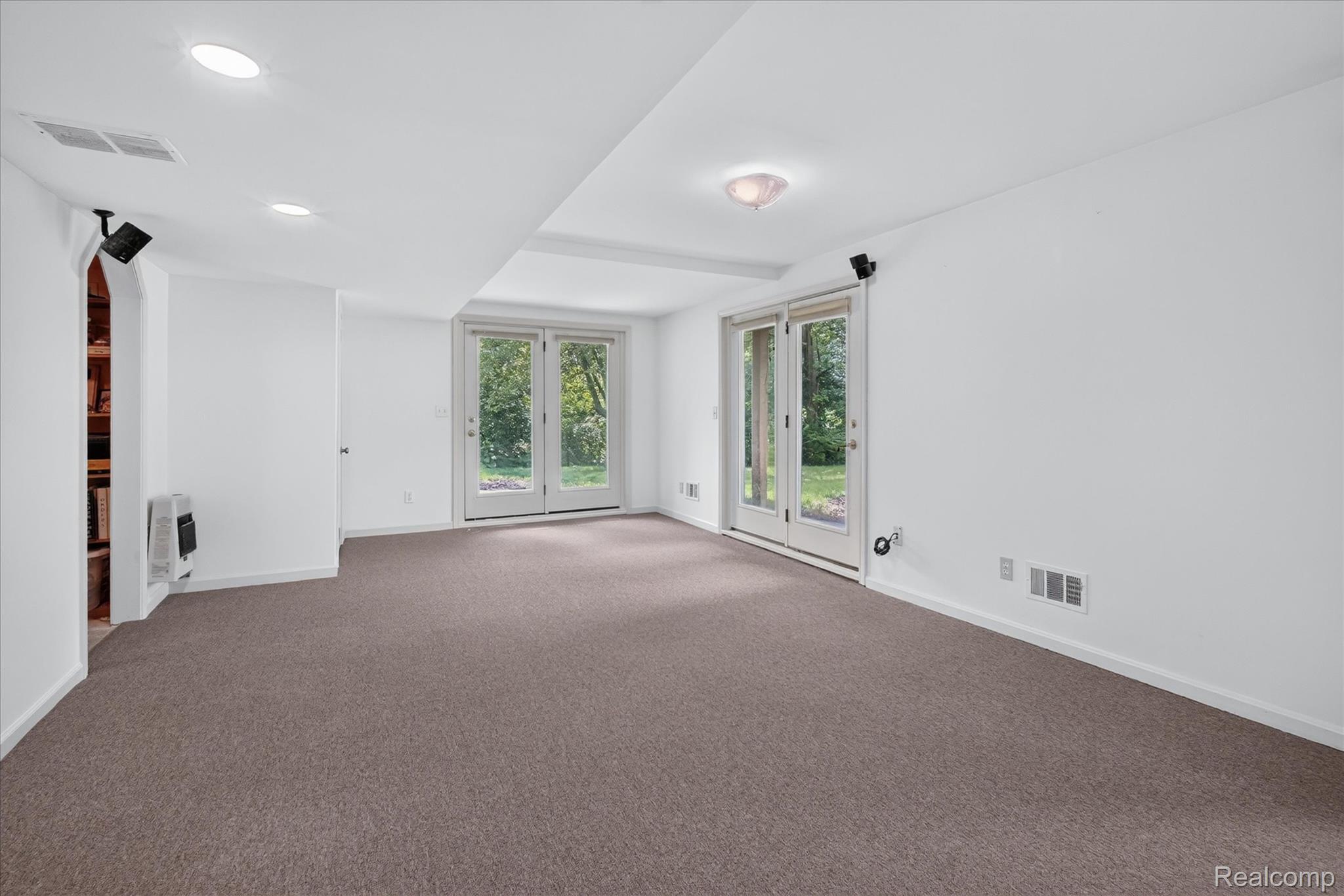 8114 Chilson Road Pinckney, MI 48169 - Photo 20 of 32 Recessed lighting illuminates this bright room featuring French doors, neutral carpeting, and a built-in bookshelf