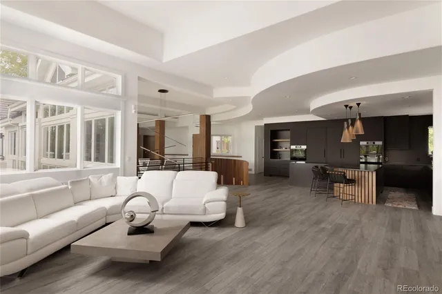 a kitchen with granite countertop a stove a sink a refrigerator and a dining table with wooden floor