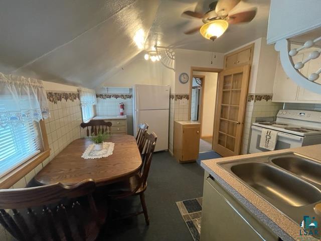 32 West Shagawa Road Ely, MN 55731 - Photo 14 of 26 Dining space featuring ceiling fan, tile walls, sink, and vaulted ceiling
