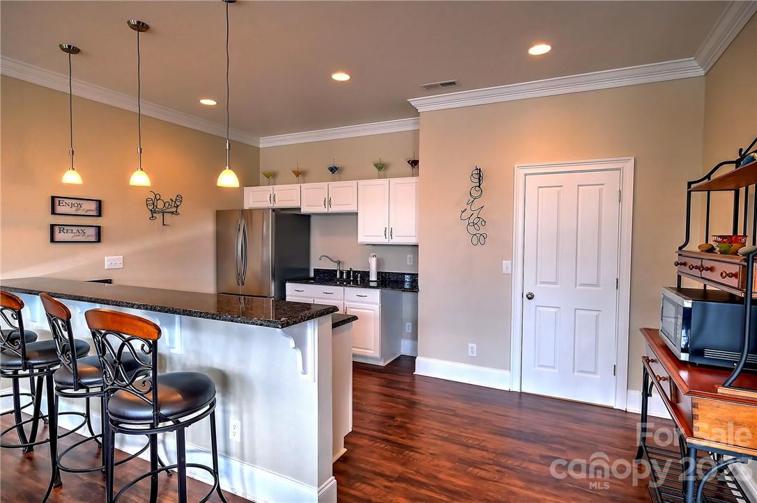 9543 Island Point Road Sherrills Ford, NC 28673 - Photo 24 of 31 a open kitchen with stainless steel appliances granite countertop a refrigerator a stove top oven a dining table and chairs with wooden floor