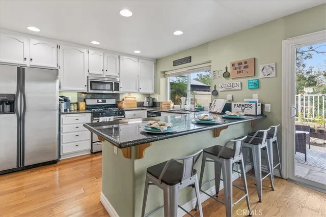 a kitchen with stainless steel appliances granite countertop a stove a refrigerator a sink a dining table and chairs