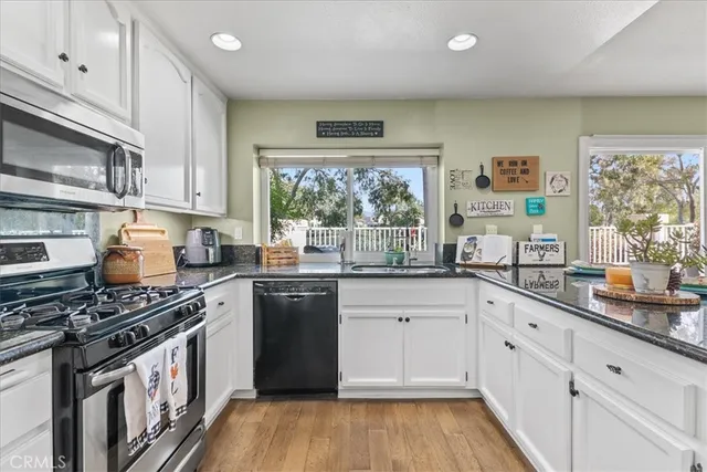 a kitchen with stainless steel appliances kitchen island granite countertop a stove a sink and white cabinets