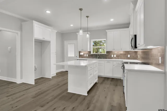 a kitchen with white cabinets appliances a sink and a window