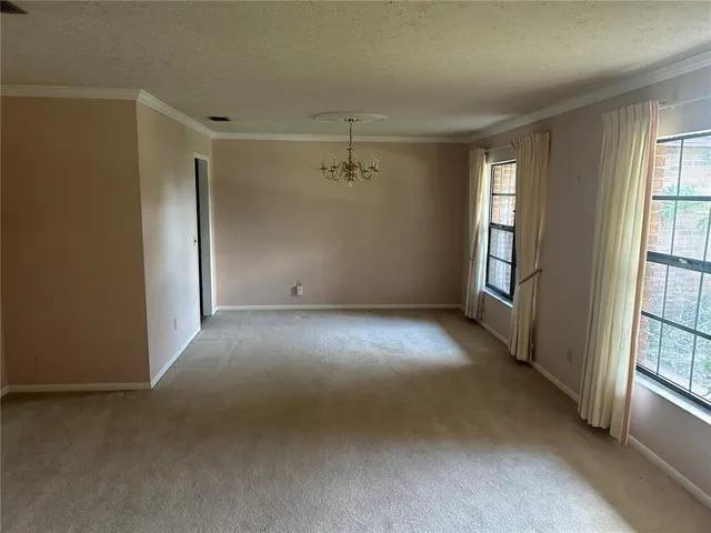a view of a big room with windows and chandelier fan