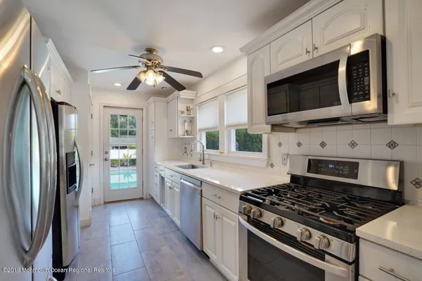 a kitchen with stainless steel appliances a stove a microwave a sink and cabinets