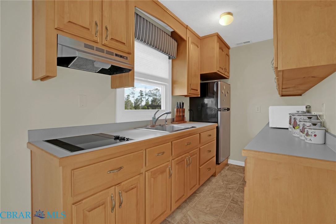 9093 Stump Point Road Hayes, VA 23072 - Photo 24 of 40 Kitchen featuring light wood cabinetry, a built-in cooktop, stainless steel range hood, stainless steel refrigerator, and a window with outdoor scenery