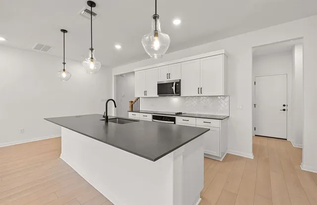 a kitchen with stainless steel appliances granite countertop a sink a stove and a wooden floors