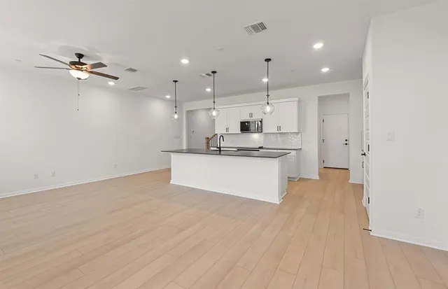 a view of kitchen with kitchen island a sink wooden floor and a refrigerator