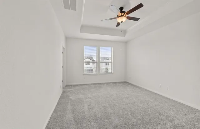an empty room with windows and fan