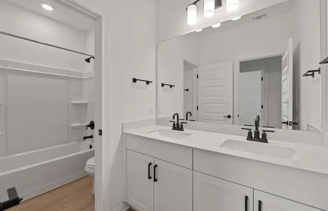 a bathroom with a double vanity sink a mirror and a bathtub