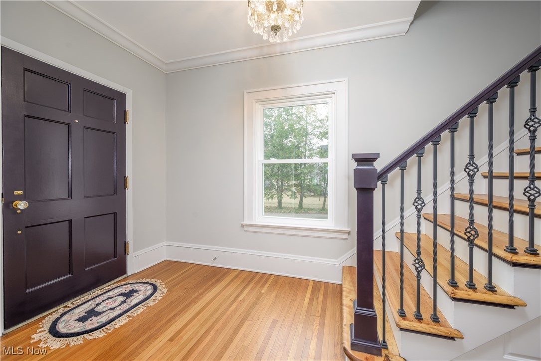 17728 Windward Road Cleveland, OH 44119 - Photo 10 of 32 Foyer featuring wood-flooring, ornamental molding, and a notable chandelier