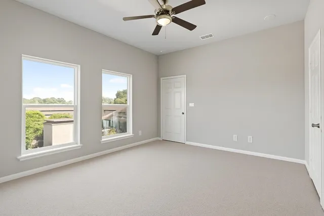 an empty room with windows and ceiling fan