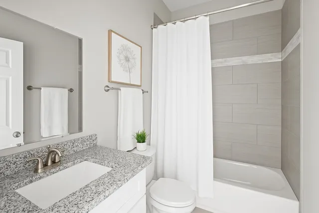 a bathroom with a granite countertop sink a toilet and shower