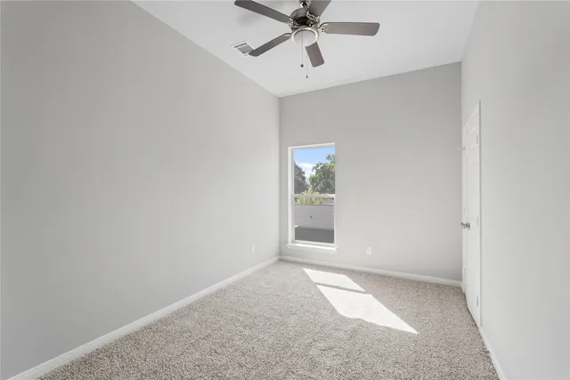 an empty room with a window and a fan
