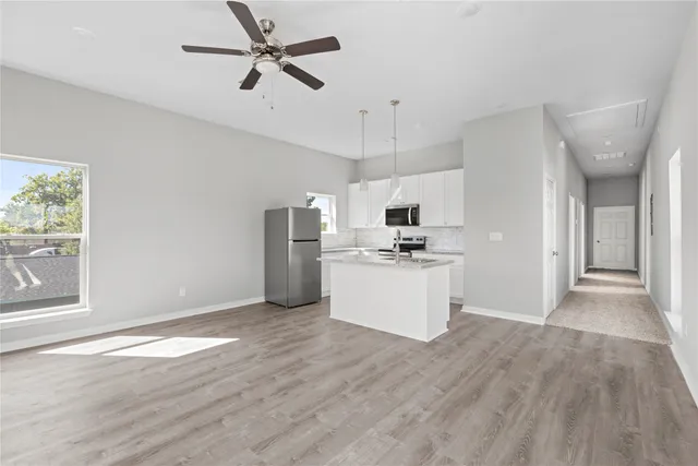 a view of kitchen with stainless steel appliances kitchen island hardwood floor and window