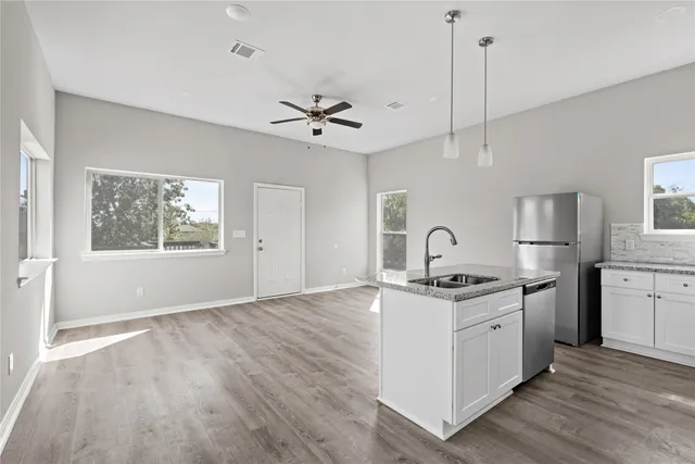 a kitchen with stainless steel appliances granite countertop a stove a sink dishwasher and a wooden floor