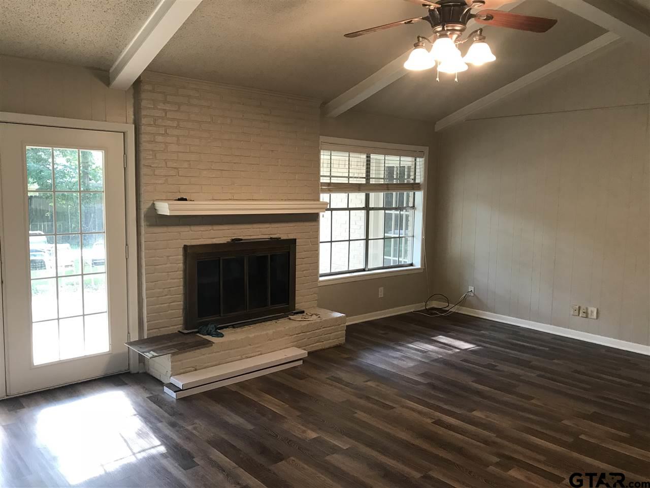 8233 Clemson Drive Tyler, TX 75703 - Photo 3 of 6 a living room with a fireplace windows and a ceiling fan