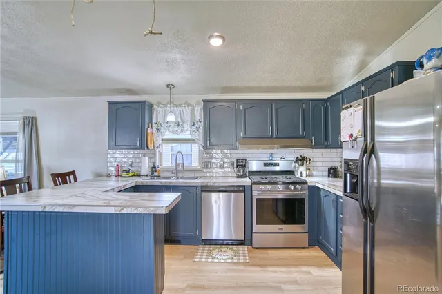 a kitchen with stainless steel appliances granite countertop a stove a sink dishwasher a refrigerator and a oven with wooden floor