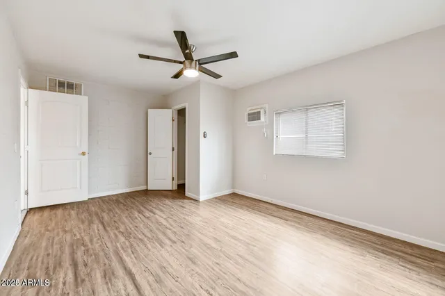 a view of empty room with wooden floor and fan