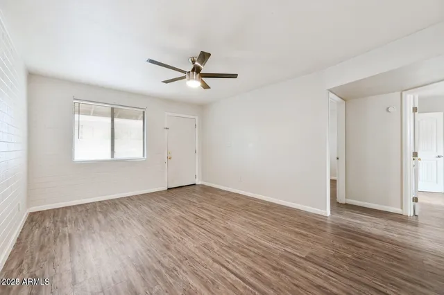 a view of empty room with wooden floor and ceiling fan