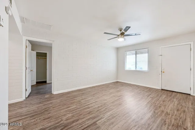 an empty room with wooden floor and ceiling fan