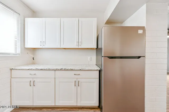 a kitchen with granite countertop white cabinets and a refrigerator