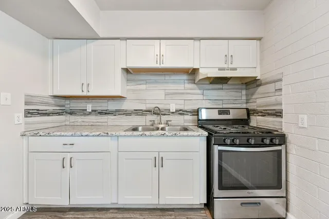 a kitchen with granite countertop white cabinets and stainless steel appliances
