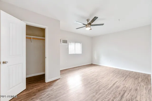 a view of empty room with wooden floor and ceiling fan