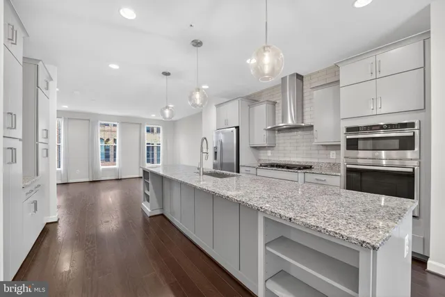 a large kitchen with stainless steel appliances granite countertop a lot of counter space and wooden floor