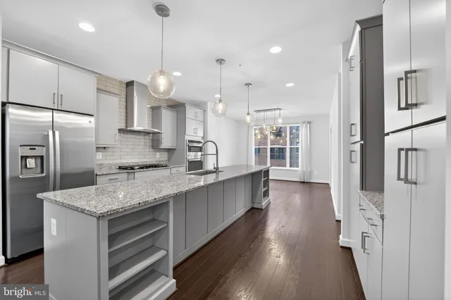 a large kitchen with granite countertop a large counter top a sink stainless steel appliances and cabinets