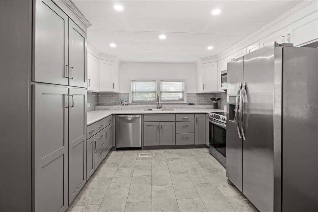 4902 91st Lane North St. Petersburg, FL 33708 - Photo 11 of 41 a kitchen with stainless steel appliances a refrigerator sink and cabinets