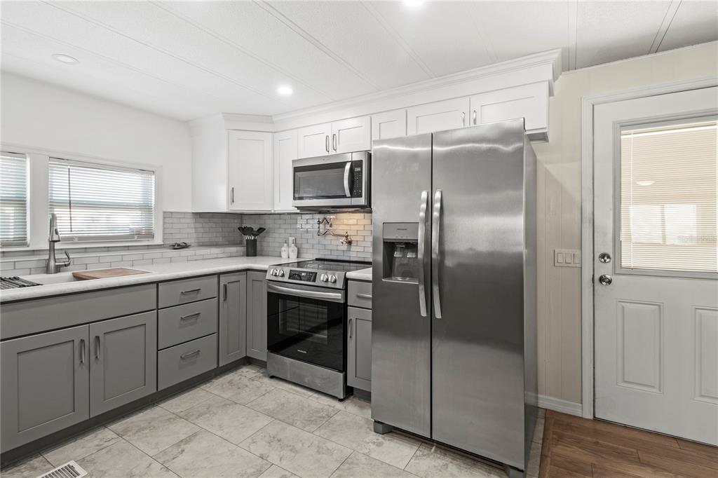 4902 91st Lane North St. Petersburg, FL 33708 - Photo 13 of 41 a kitchen with stainless steel appliances granite countertop a refrigerator a sink and white cabinets