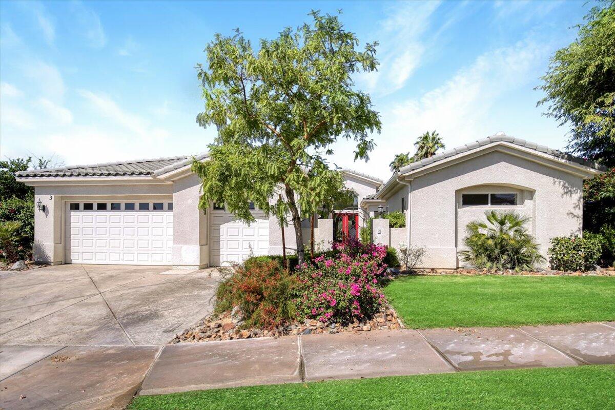 a front view of a house with a garden and trees
