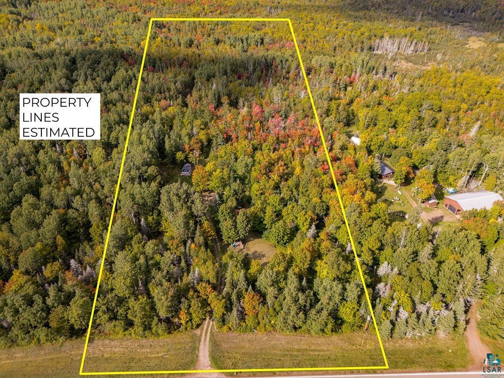 1159 Wales Road Two Harbors, MN 55616 - Photo 24 of 29 Expansive wooded property featuring a cleared building site, a gravel access path, and a structure with a gray roof