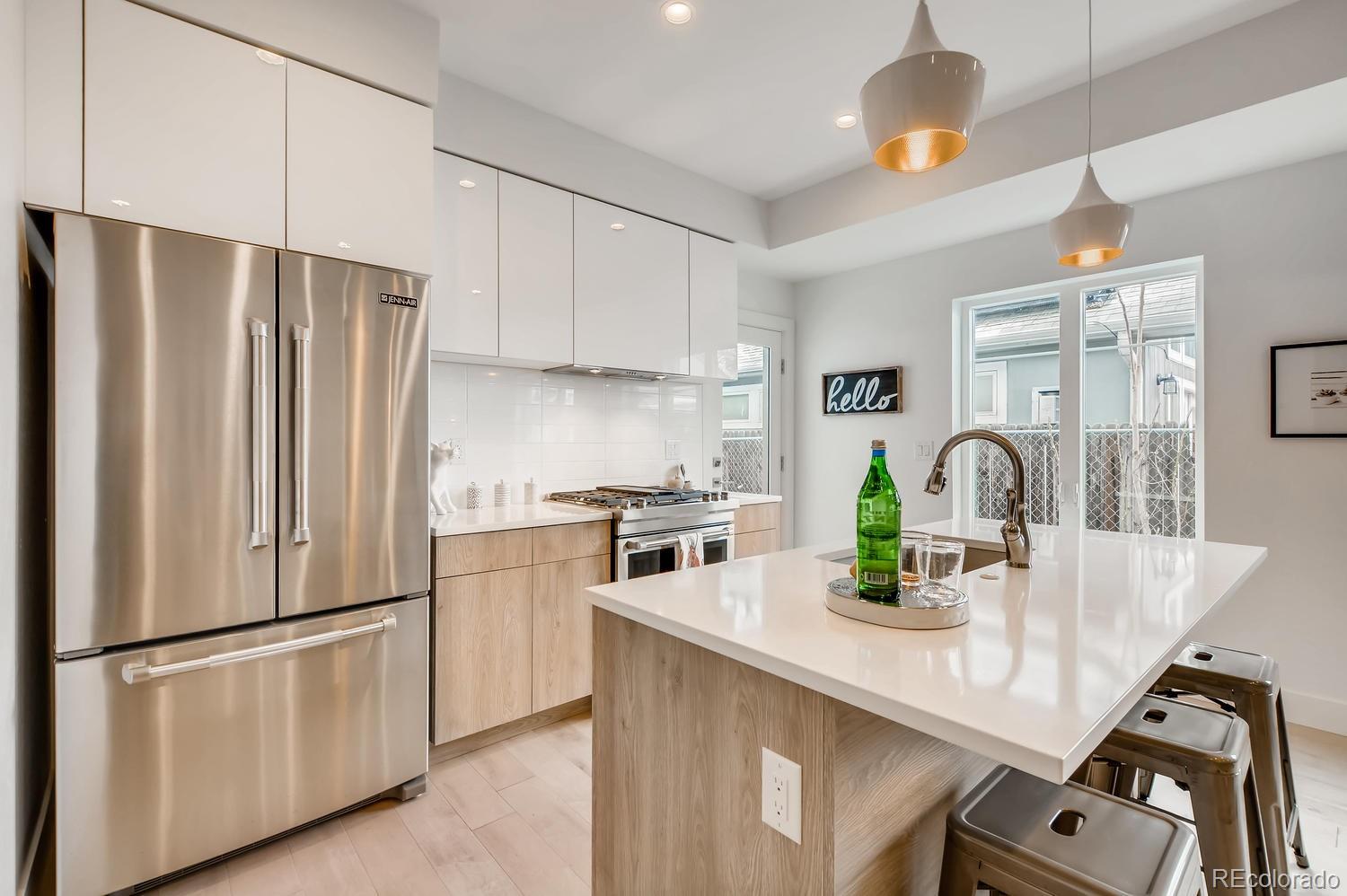 234 Inca Street Denver, CO 80223 - Photo 23 of 27 a kitchen with stainless steel appliances a refrigerator a sink a stove and white cabinets with wooden floor