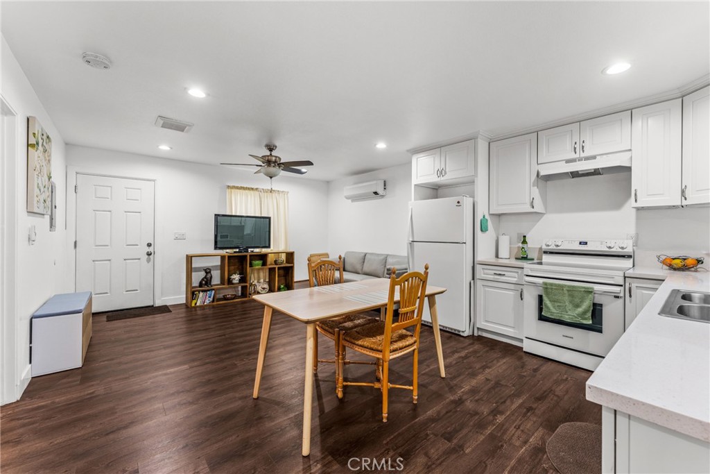 7977 Vista Del Rosa Street Downey, CA 90240 - Photo 32 of 53 a kitchen with stainless steel appliances kitchen island granite countertop a table chairs stove and white cabinets