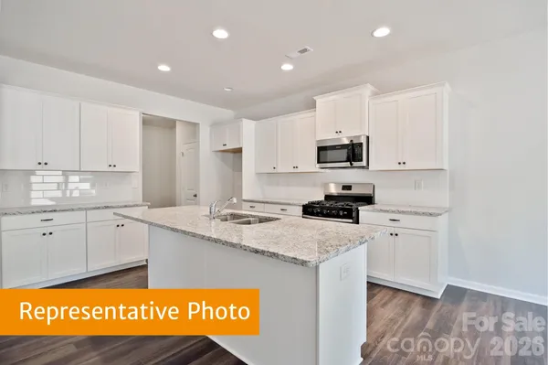 a kitchen with granite countertop a sink stainless steel appliances and white cabinets
