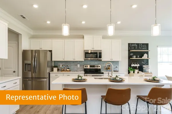 a kitchen with stainless steel appliances kitchen island granite countertop a refrigerator a stove a sink a dining table and chairs with wooden floor