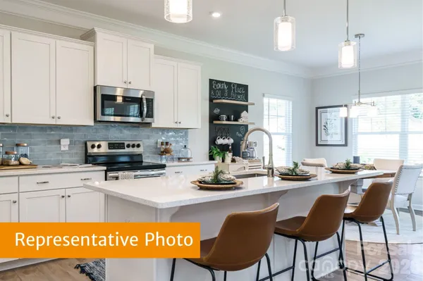 a kitchen with stainless steel appliances kitchen island granite countertop a sink white cabinets a dining table and chairs