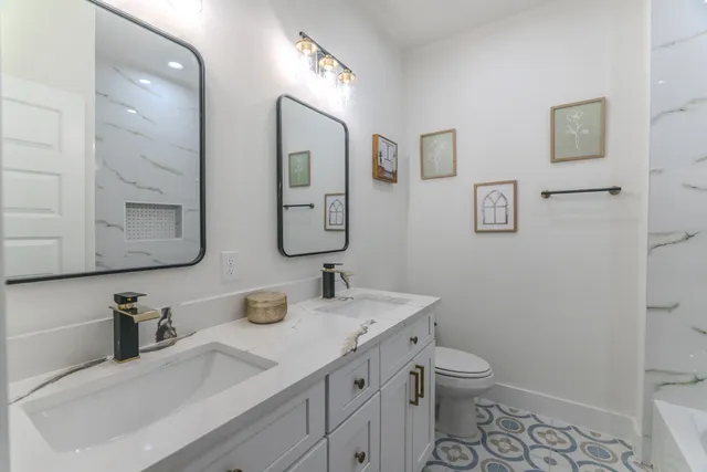 a bathroom with a granite countertop sink mirror vanity and toilet