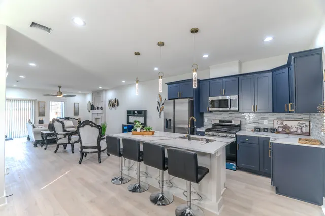 a kitchen with stainless steel appliances kitchen island granite countertop a stove a sink a dining table and chairs