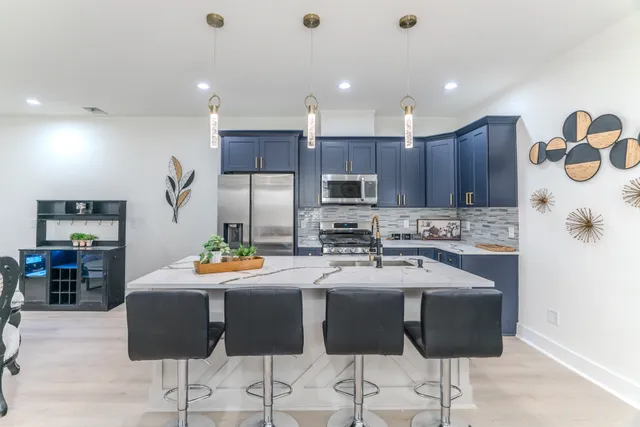 a kitchen with stainless steel appliances kitchen island granite countertop a dining table and chairs in it