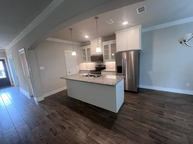 a kitchen with kitchen island granite countertop a sink appliances and cabinets